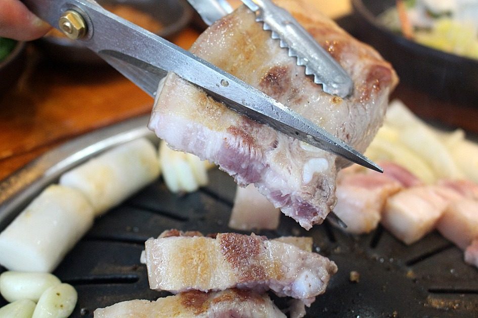 호치민 고기집에서 가위로 삼겹살을 자르는 모습